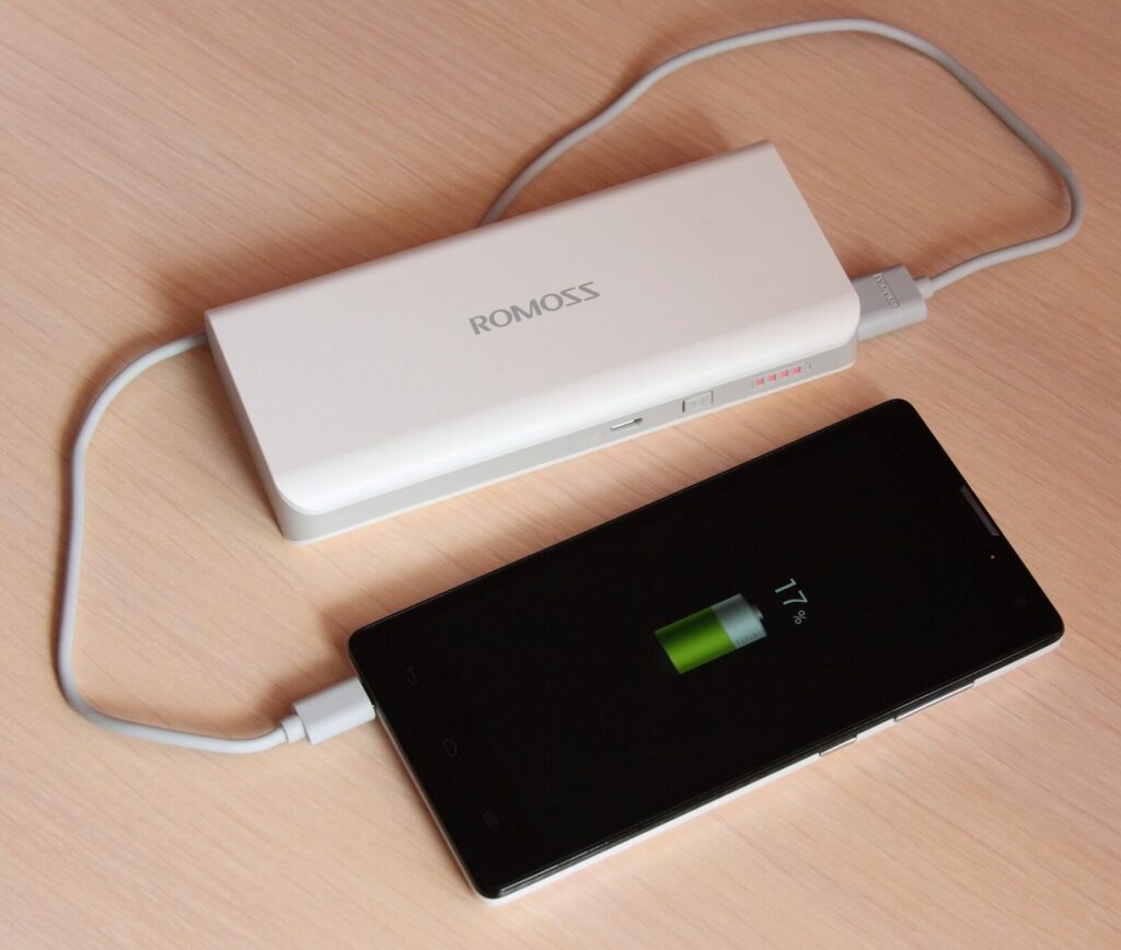 Power bank portátil cargando un celular con cable