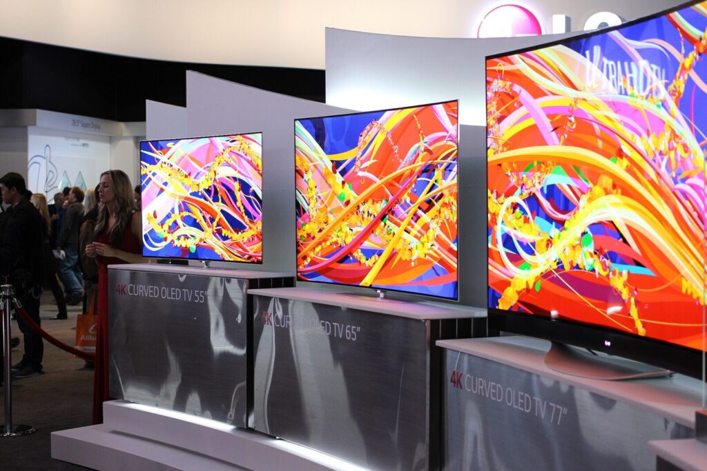 Fila de televisores 4K OLED curvos con pantallas coloridas